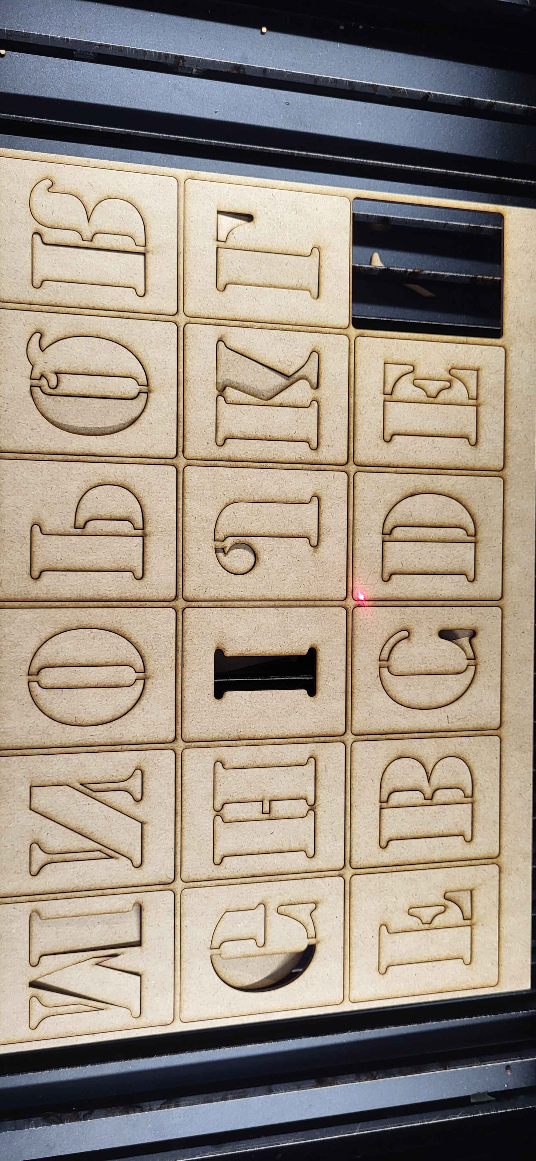 Set of laser-cut letters on a wooden board

